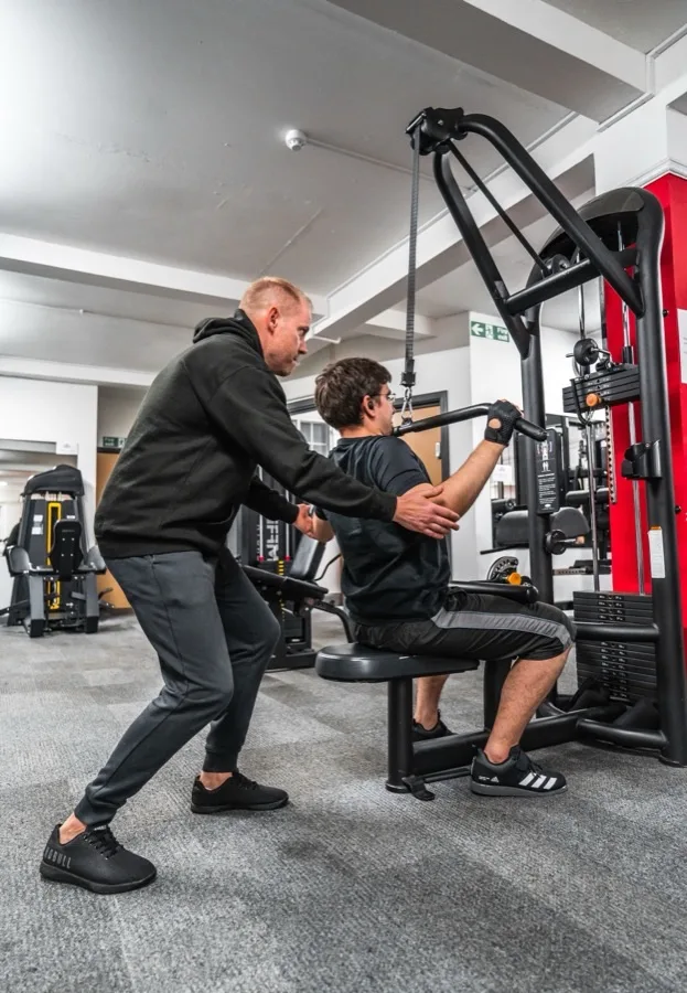 Dennis, coach bij Studio Kracht, begeleidt training op de kabelmachine
