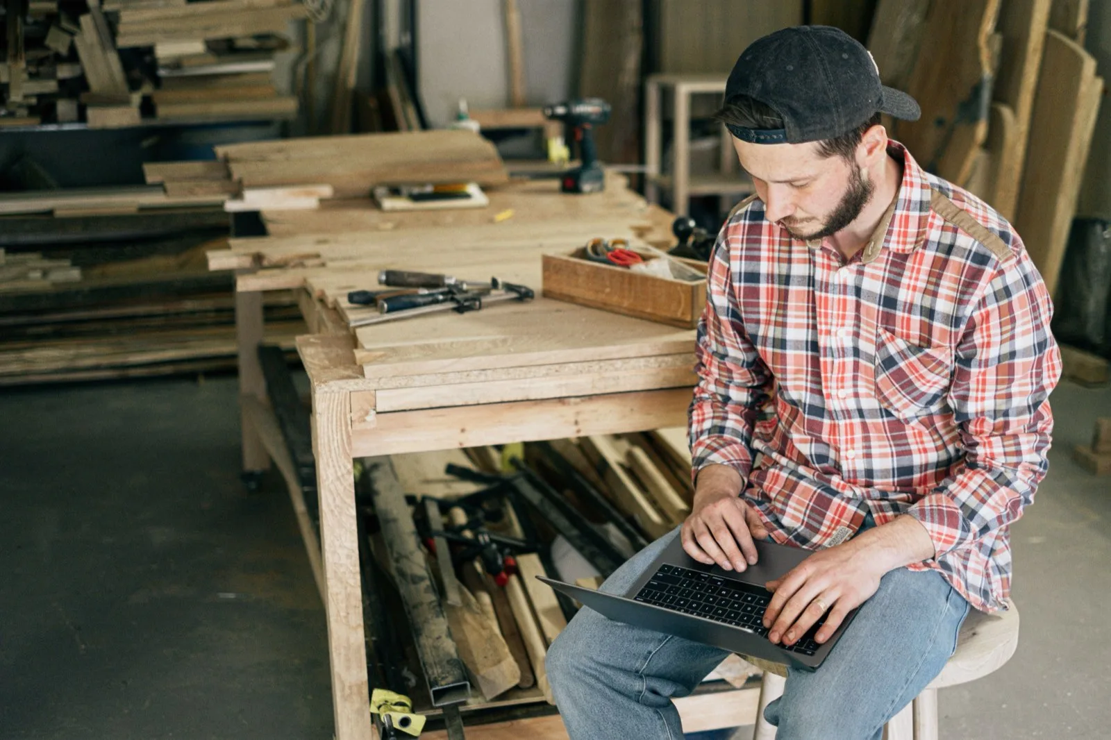 Een vakman met laptop tussen het gereedschap in zijn werkplaats
