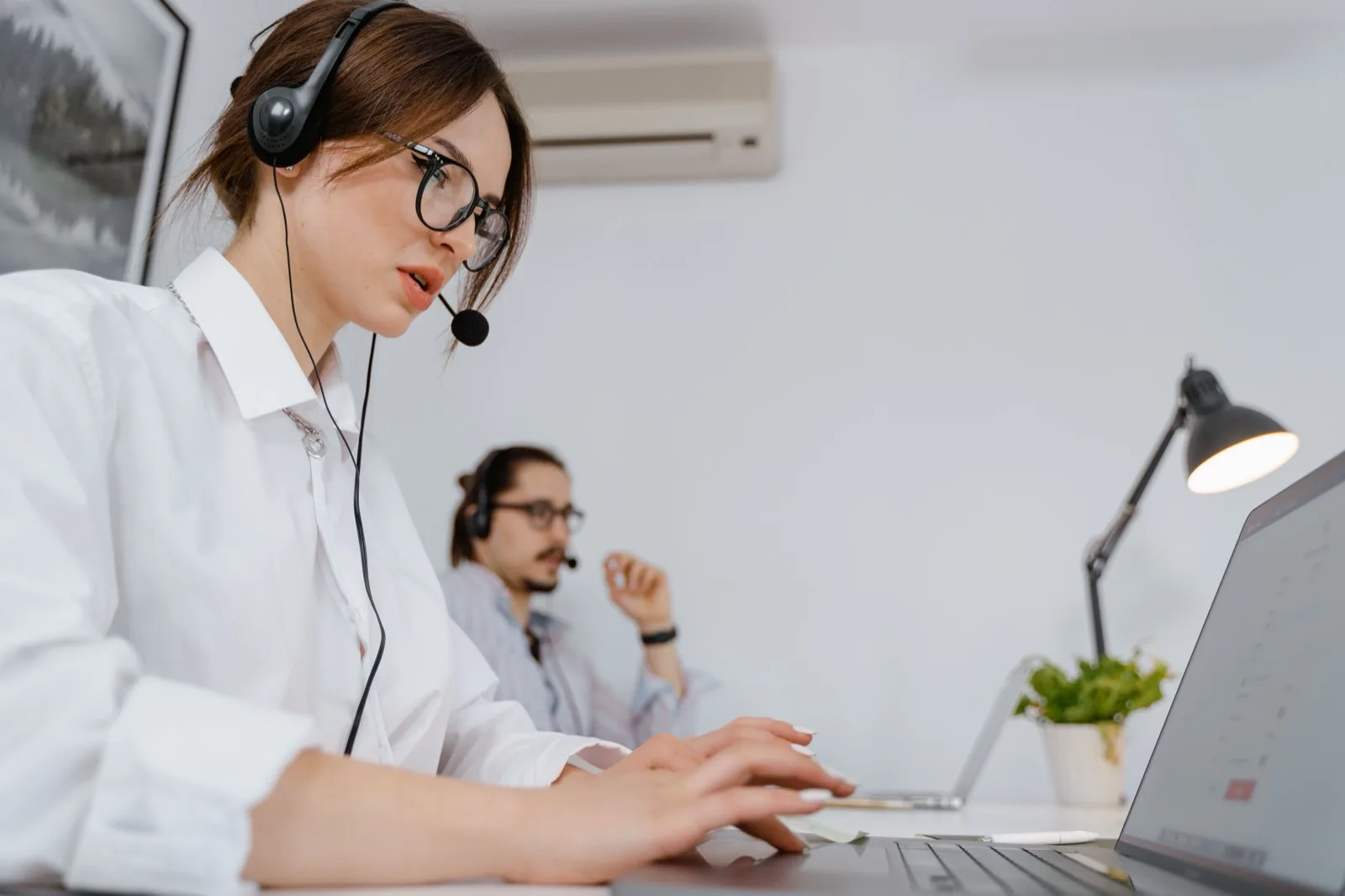 Klantenservice-medewerkers met headset aan het werk achter een laptop